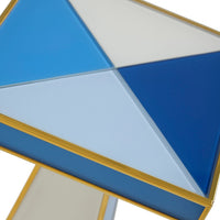 Close-up of a geometric side table top with triangular panels in blue, light blue, and white, framed by a gold metal border.