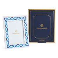 Two Jonathan Adler picture frames, one white with blue geometric design and the other navy with gold lettering.