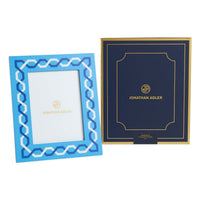 Two Jonathan Adler frames, one blue with geometric pattern and gold text, the other navy with gold border and text.