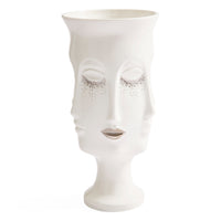A white ceramic vase sculpted in the shape of a stylized female face with closed eyes and delicate silver glitter accents around the eyes, set against a plain white background.