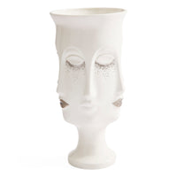 A white ceramic sculptural vase shaped like a stylized female face with closed eyes, decorated with silver glitter accents under the eyes and on the cheeks, set against a plain white background.