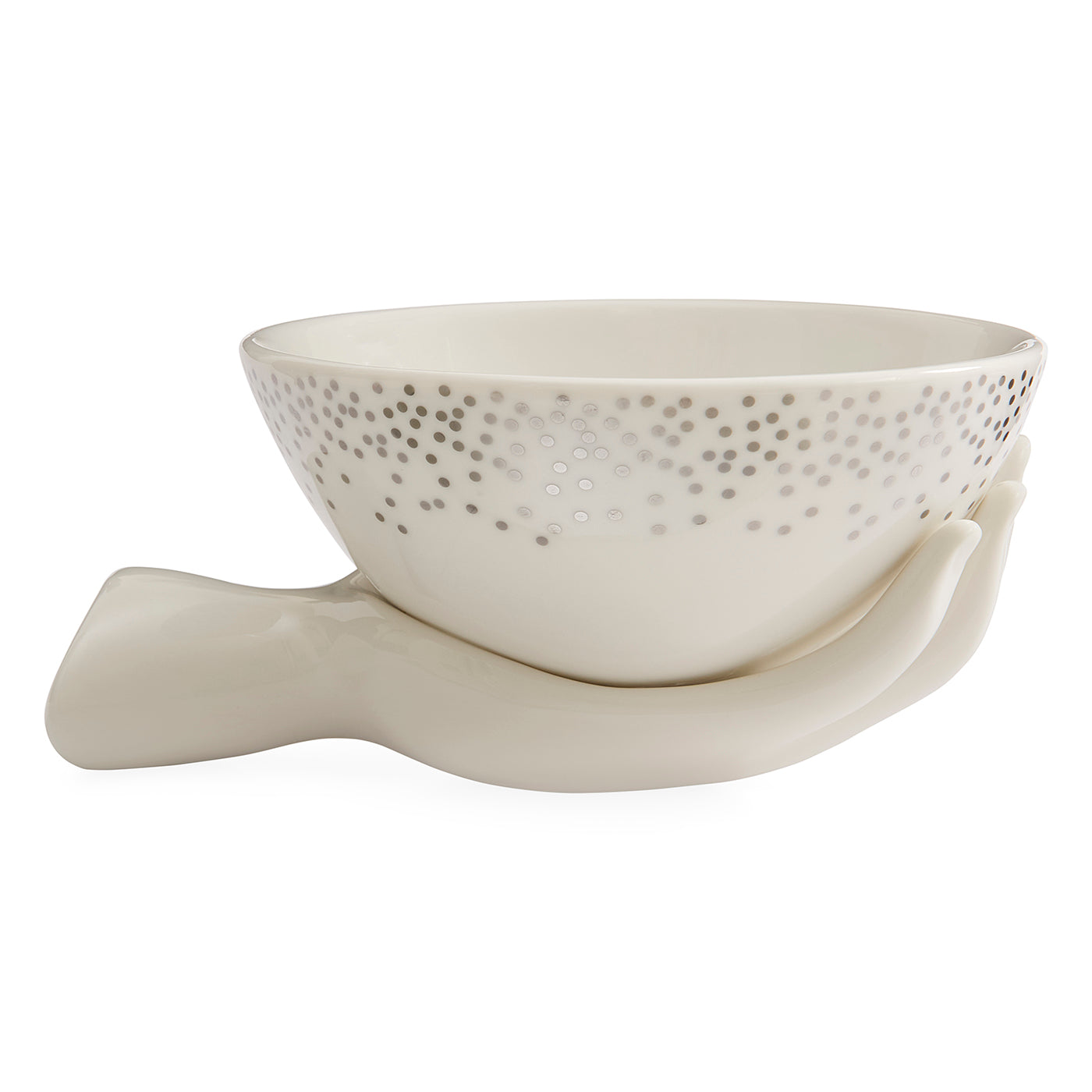 An off-white ceramic bowl with a dotted pattern on the exterior, nestled in a sculptural ceramic hand-shaped base, set against a plain white background.