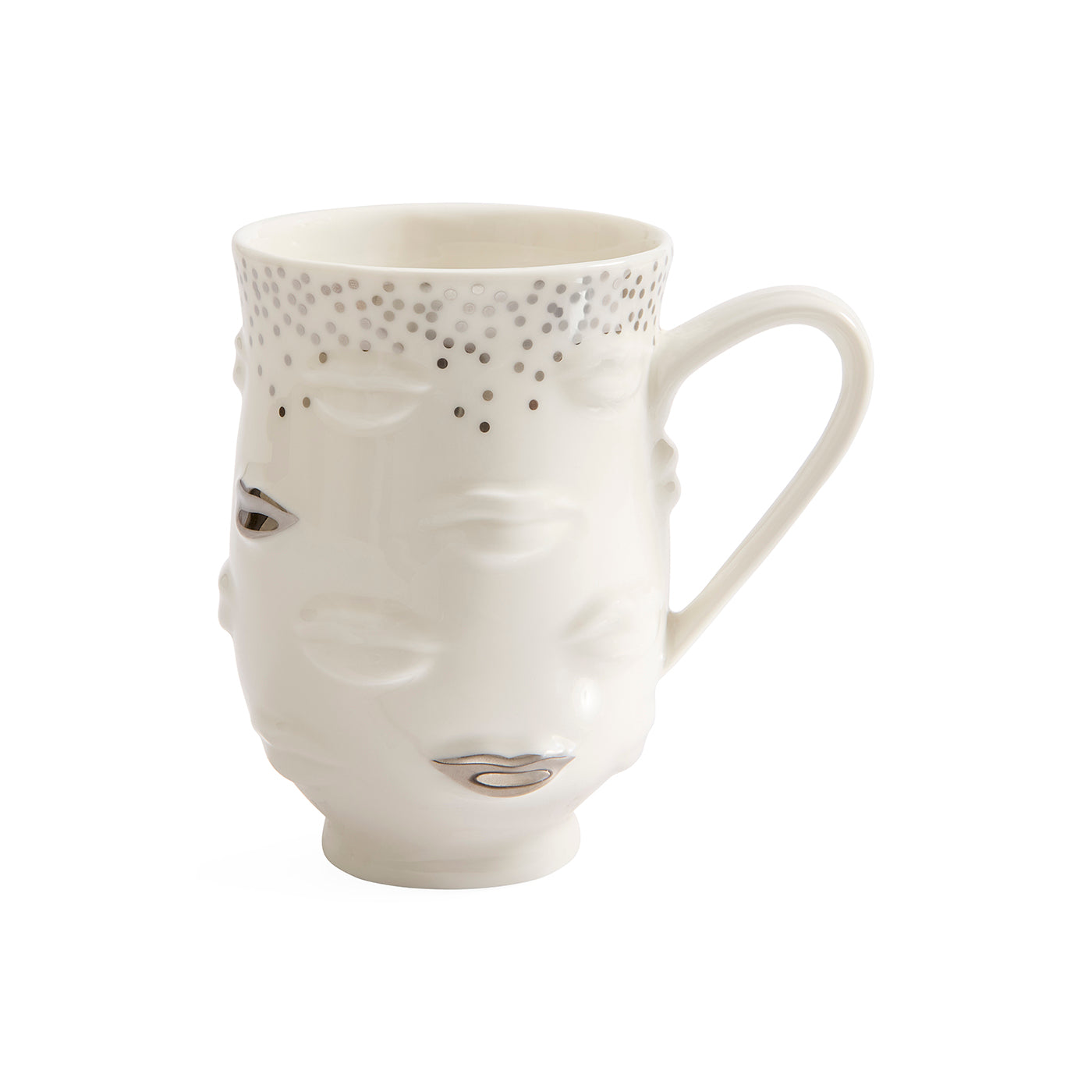A white ceramic mug featuring a sculpted face with closed eyes, metallic silver details on the lips and forehead, and a dotted pattern near the rim, set against a plain white background.