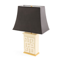 Table lamp with a black shade and decorative white base on a white background