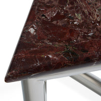 Close-up of a triangular table corner with a polished dark red-brown marble top showing natural veining, supported by a shiny silver metal frame on a white background.