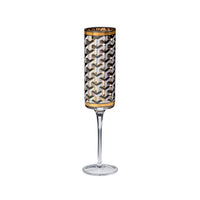 A clear stemmed glass featuring a cylindrical patterned body with a black, white, and gray geometric cube design and gold trim at the top and bottom, shown on a plain white background.