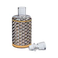 A clear glass decanter with a geometric interlocking cube pattern in black, white, and gold, shown with its clear glass stopper on a white background.