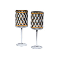 Two clear stemmed glasses with cylindrical bodies featuring a black, white, and gold geometric cube pattern, shown on a plain white background.