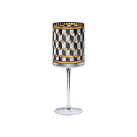 A clear stemmed wine glass with a cylindrical patterned bowl featuring a black, white, and gold geometric cube design.