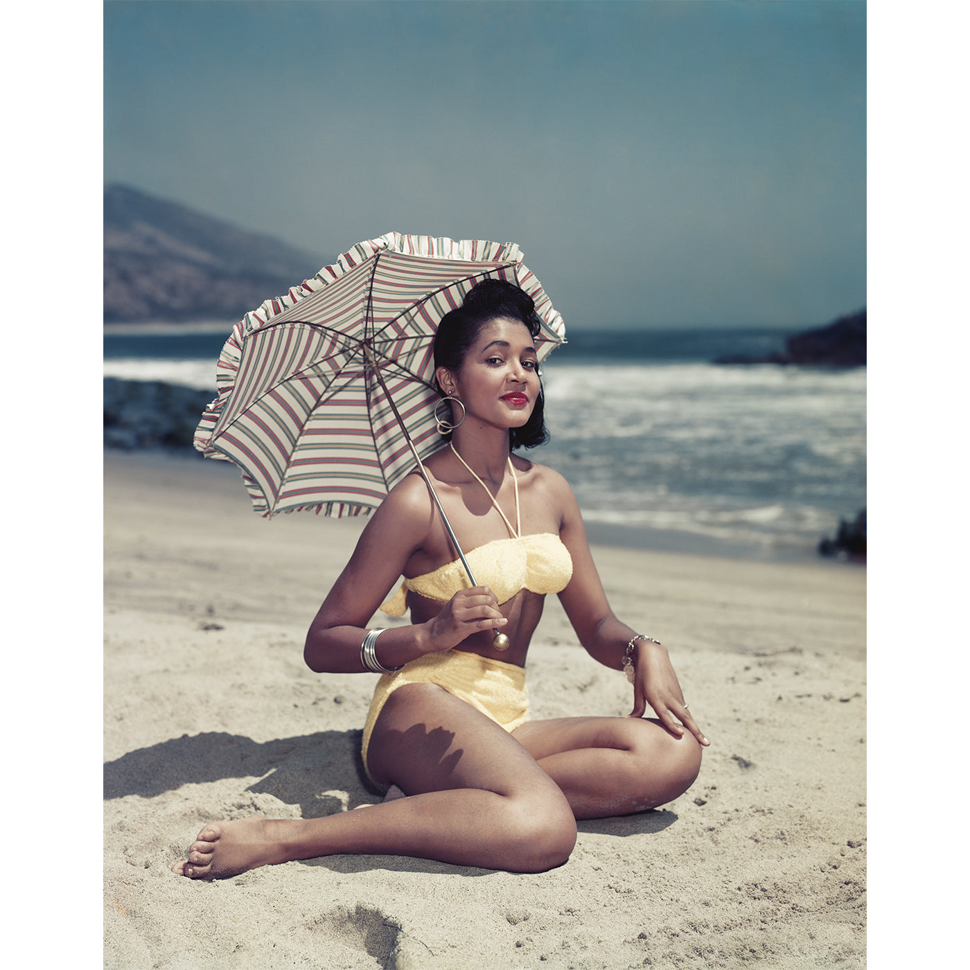 "woman on beach holding umbrella" from getty images - front view
